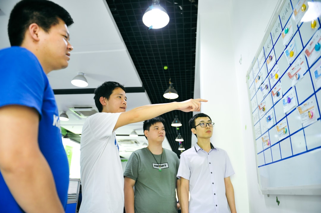 Four men in a modern office looking at a task board with magnets for How We Redesigned Our Client Onboarding Process to Cut Project Timeline by 30%