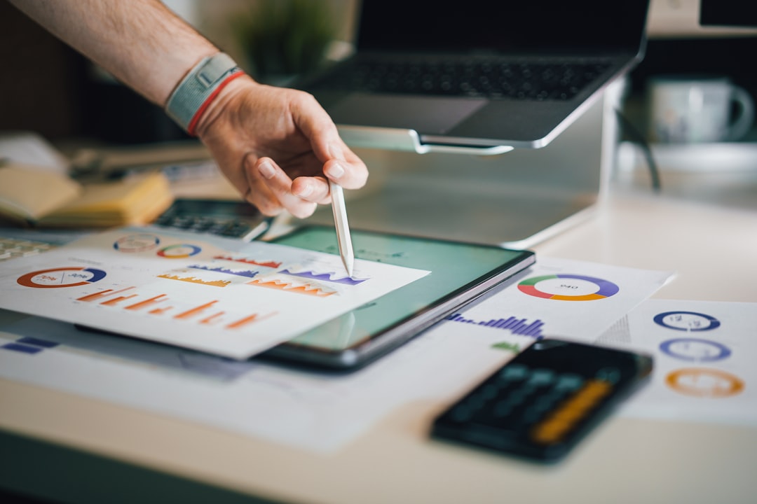 Person using stylus on tablet with charts for The Complete Guide to Choosing Between Figma, Adobe XD, and Sketch for Your Small Business Website Redesign