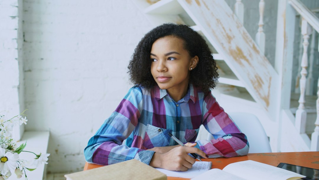 Young woman writing at a table with open book for How to Create a Consistent Posting Schedule That Actually Drives Engagement for Small Businesses