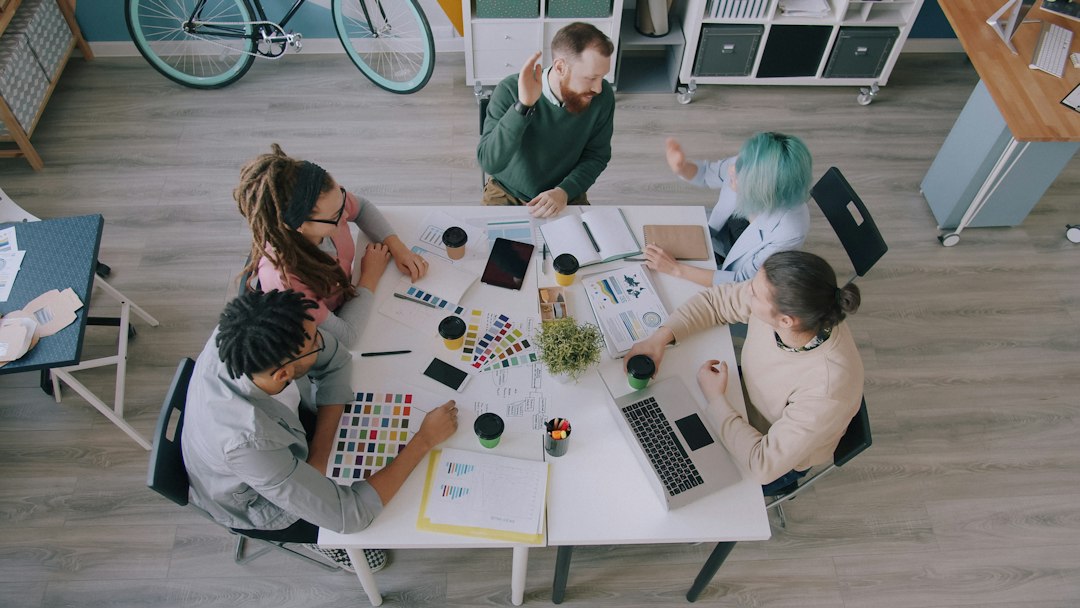 A group of five people collaborating around a white table in a workspace