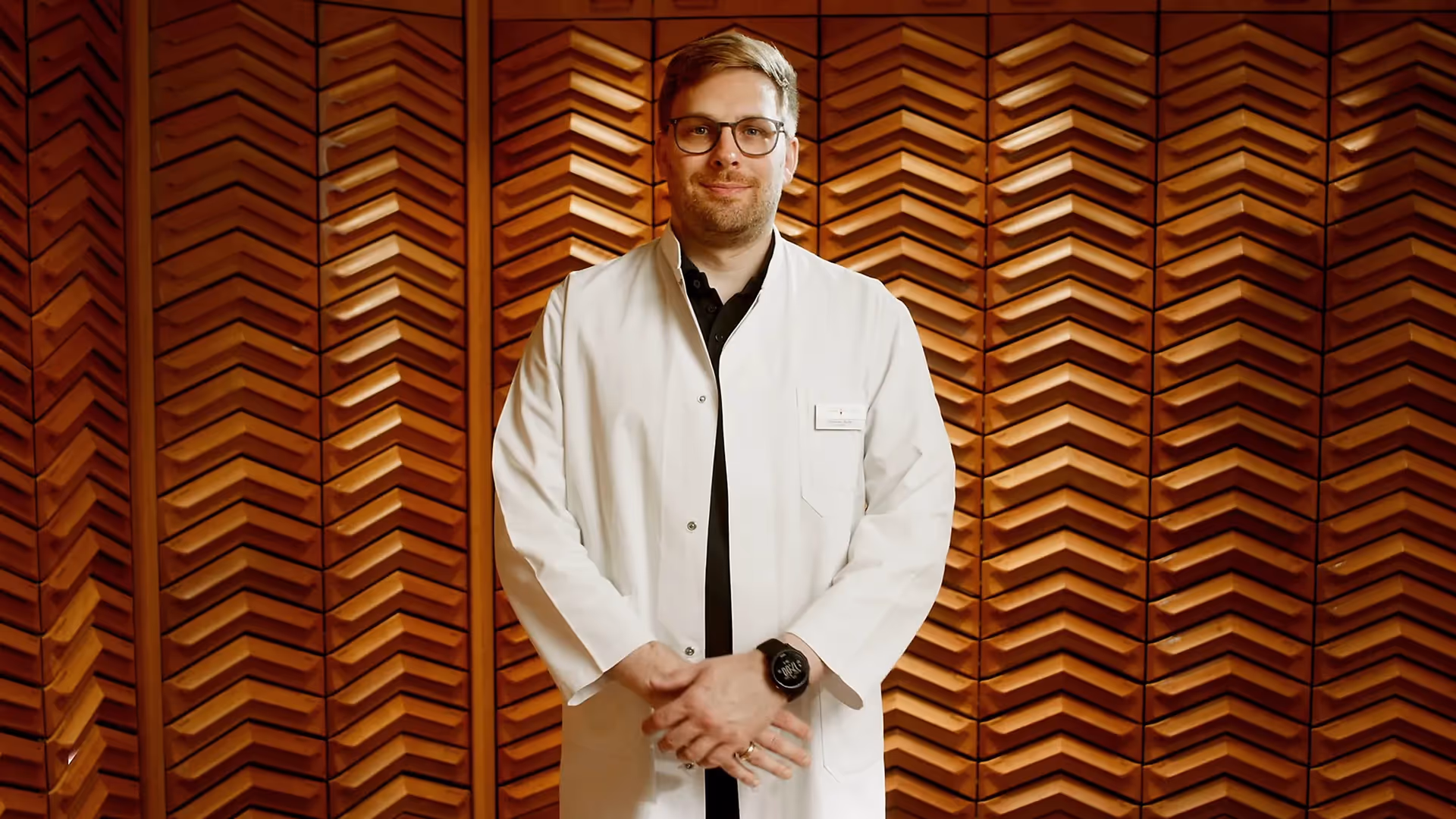 Apotheker im weißen Kittel steht vor Holzwand, pharmazeutische Beratung in Apotheke.