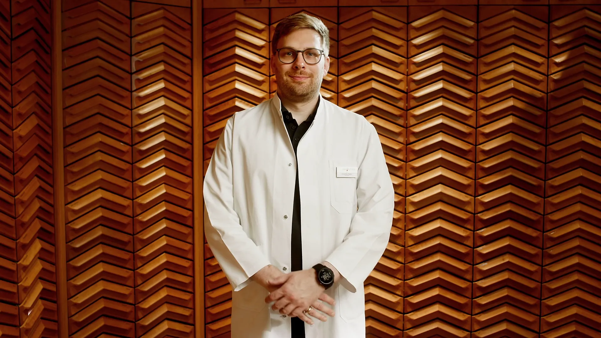 Apotheker im weißen Kittel steht vor Holzwand, pharmazeutische Beratung in Apotheke.