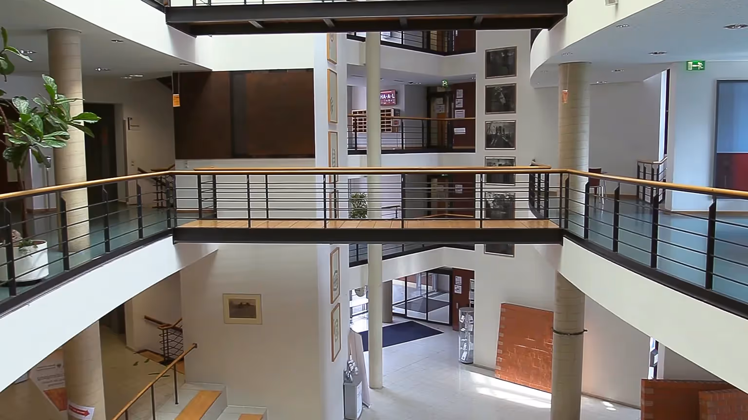 Recruitingfilm Szene: Modernes Atrium einer Hochschule mit offenen Galerien, hellen Wänden und Kunstwerken – visuelle Darstellung von Architektur, Bildung und Campusleben in hochwertiger Filmproduktion und Recruitingfilm.