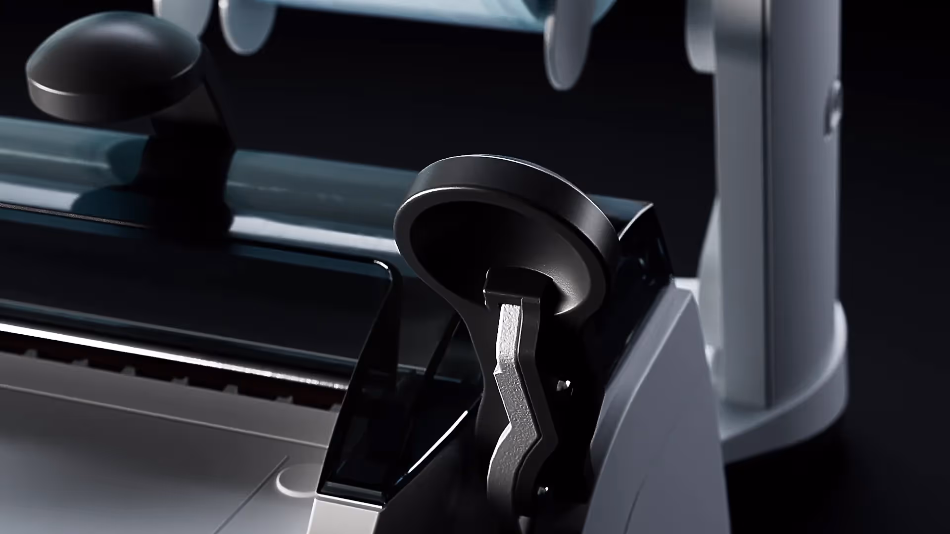 Nahaufnahme eines modernen Geräts mit schwarzem Griff und glänzender Oberfläche vor dunklem Hintergrund.