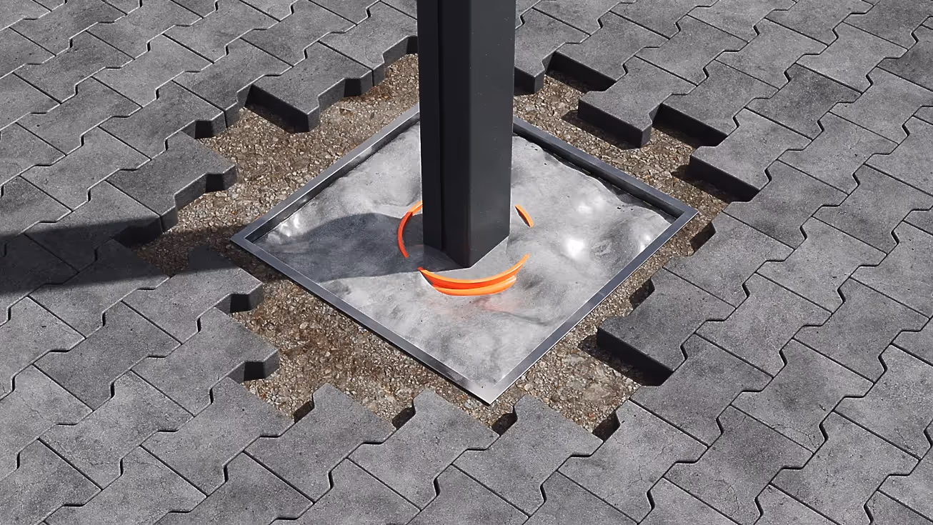 3D-Rendering einer quadratischen Bodenverankerung mit Metallrahmen und Betonfundament, in dem ein dunkler Pfosten befestigt ist, umgeben von grauen Pflastersteinen mit sichtbarer Erdschicht darunter.