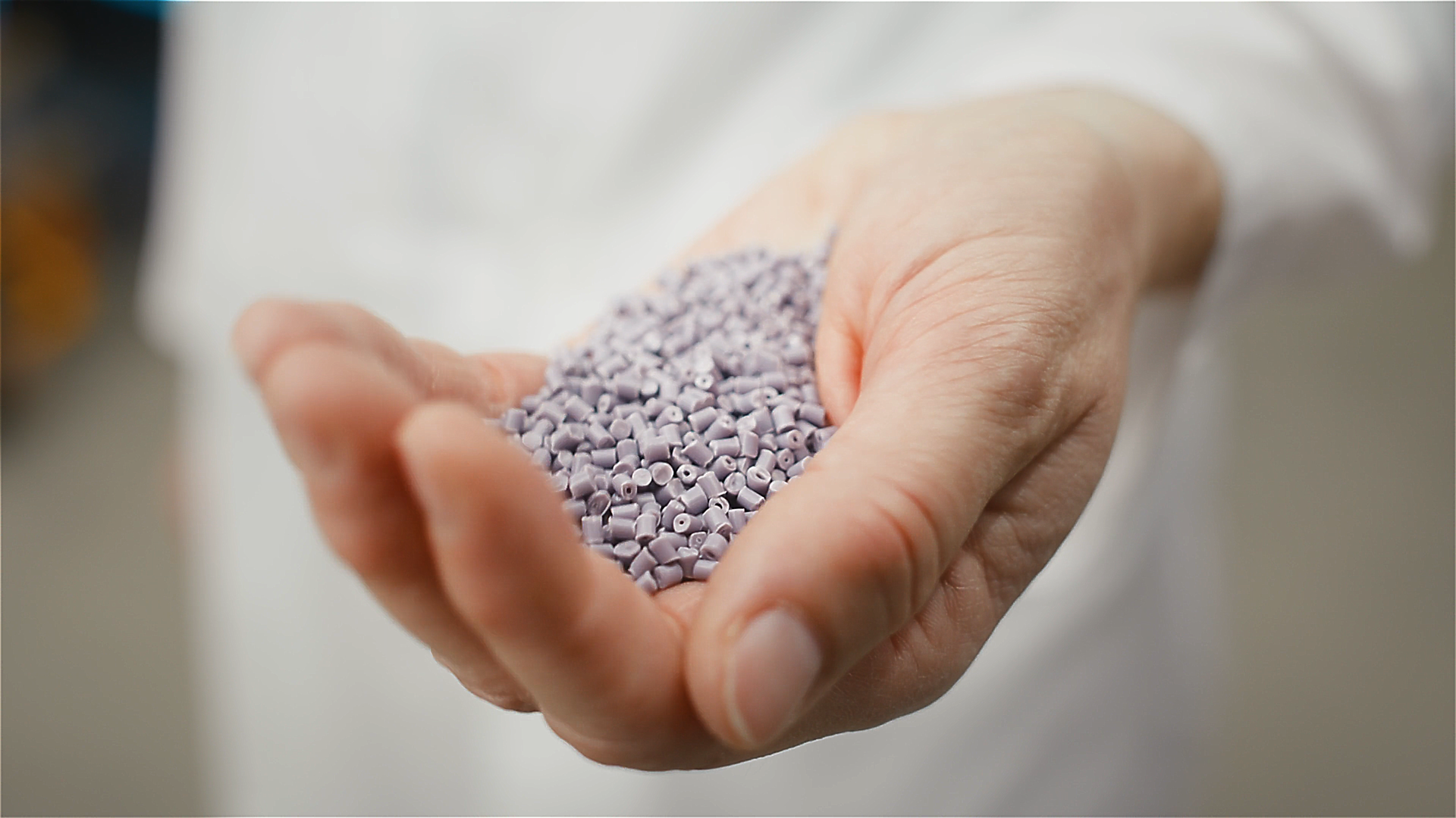 Nahaufnahme: Hand hält kleine lila Granulate – nachhaltige Rohstoffe und Zutaten für Fischfutterentwicklung.