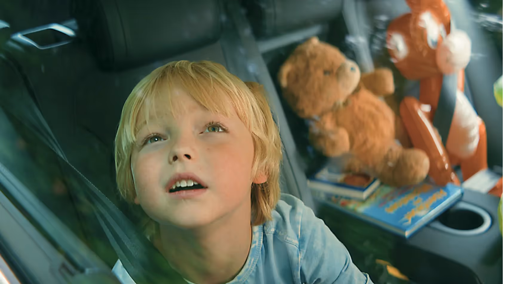Junge sitzt auf Rücksitz schaut aus dem Autofenster mit Stofftieren FEBI Werbefilm.