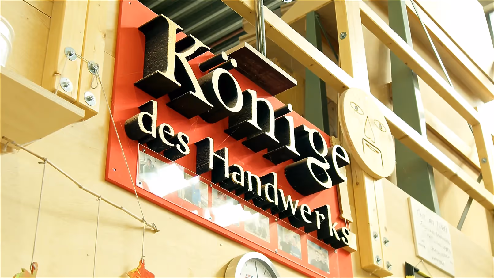 Imagefilm Szene: Ein großes Schild mit der Aufschrift „Könige des Handwerks“ hängt in einer Werkstatt – symbolische Darstellung von Bildung, Handwerk und Stolz im Imagefilm über Ausbildung und Fachkräfte.