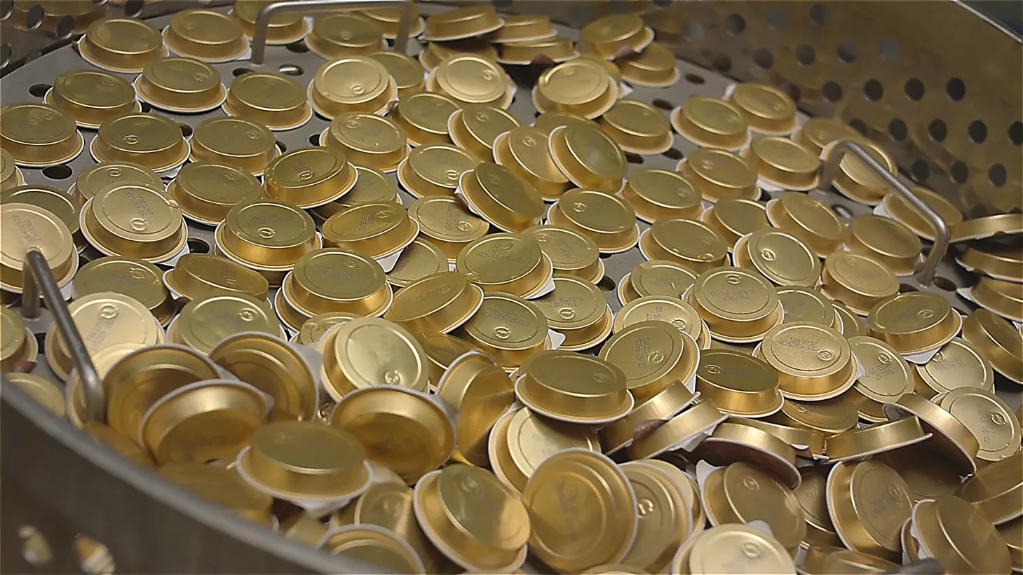 Industrielle Produktion: goldene Futterschalen stapeln sich in einer Metallwanne, glänzende Deckel in Massenproduktion – Tiernahrungsfertigung.