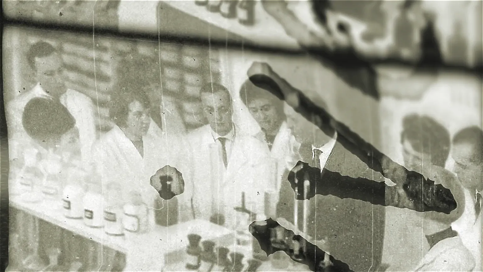 Historisches Schwarzweißfoto: Gruppe von Forschern im weißen Kittel im Labor, beschädigter Film mit Kratzern und Flecken – Rückblick auf frühe Forschung.