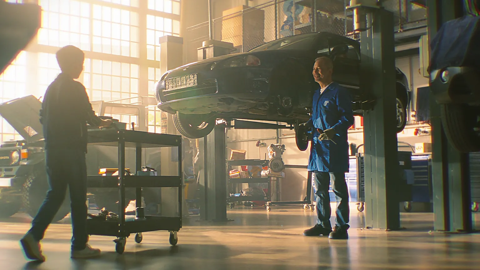 Zwei Mechaniker arbeiten in einer hellen Autowerkstatt mit Fahrzeug auf Hebebühne.