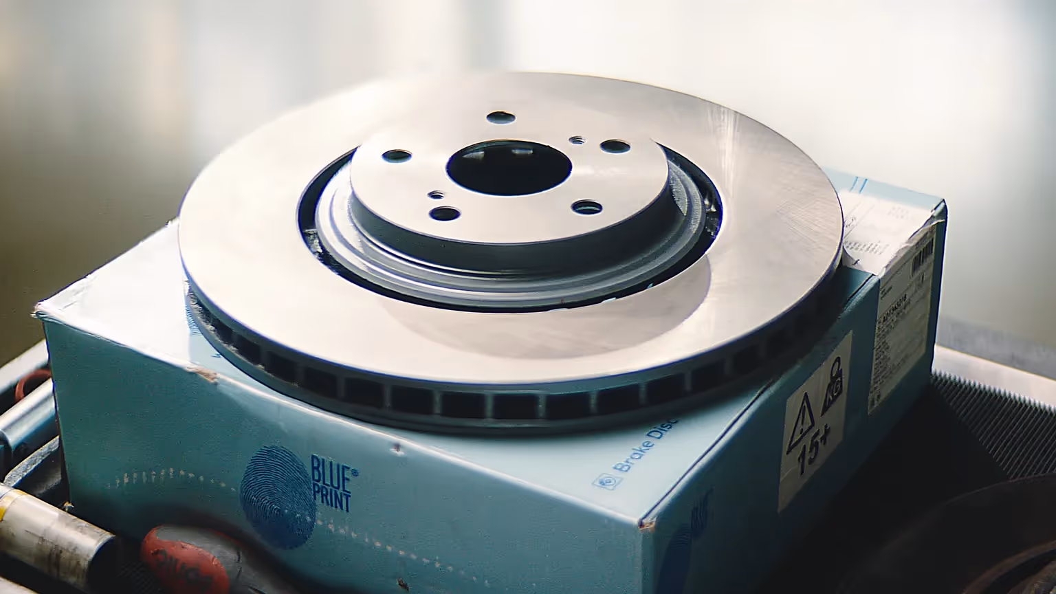 Nahaufnahme einer neuen Bremsscheibe von Blue Print auf Verpackung in einer Werkstatt.