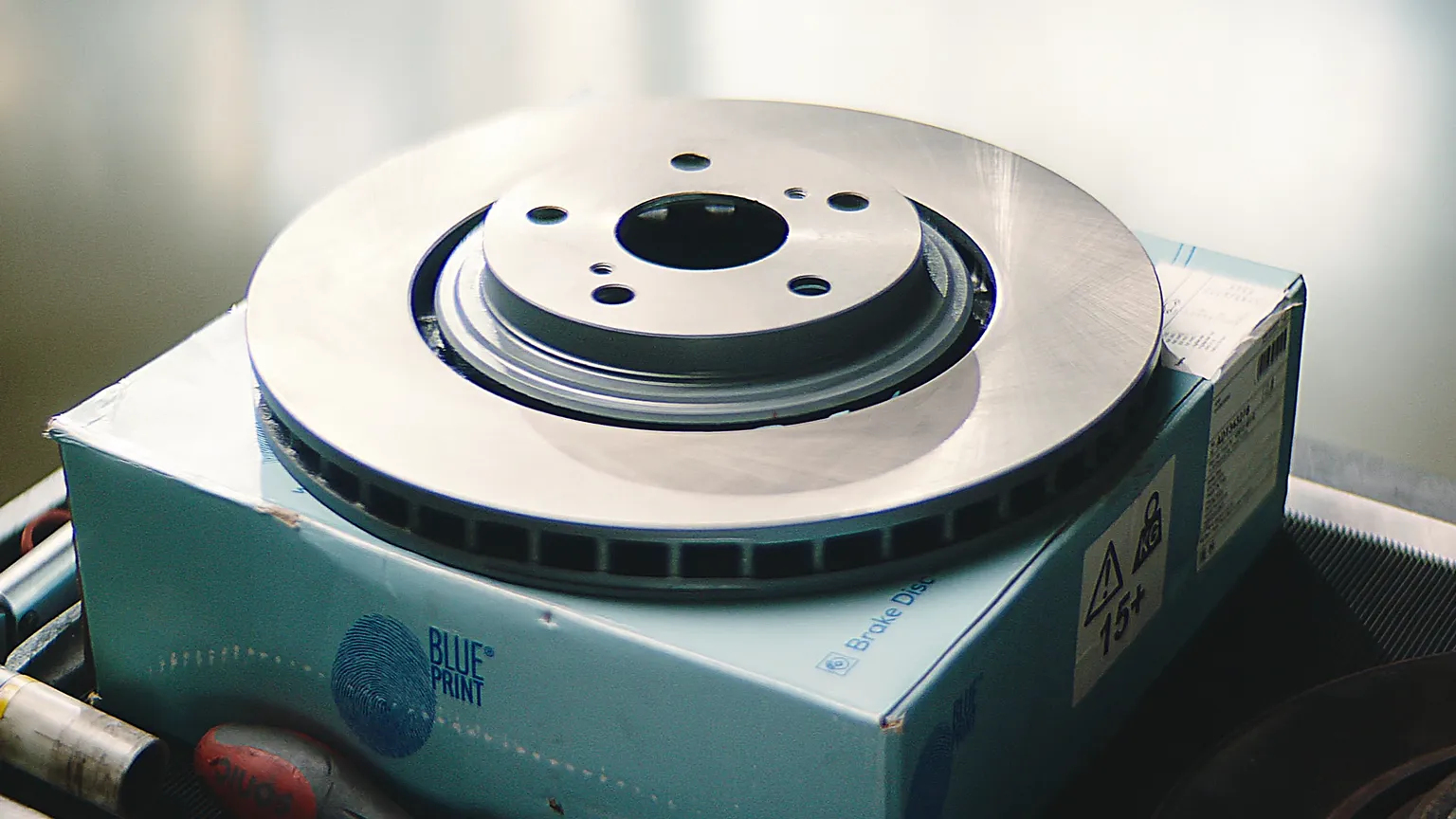 Nahaufnahme einer neuen Bremsscheibe von Blue Print auf Verpackung in einer Werkstatt.