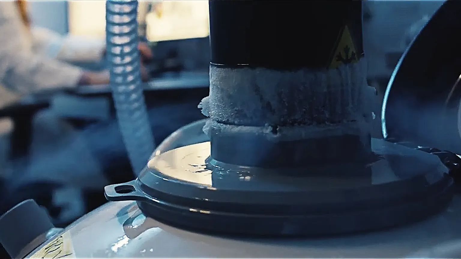 Nahaufnahme eines Laborgeräts mit Vereisung und angeschlossenem Schlauch, Symbol für moderne Kryotechnik.