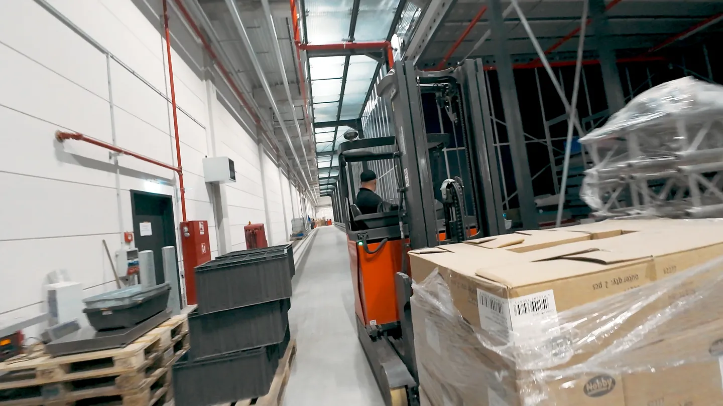 Kundenfilm Szene: Ein Mitarbeiter fährt Gabelstapler im Nobby Lager – Darstellung effizienter Warenlogistik, Transport und Kommissionierung im Logistikzentrum, visualisiert im Kundenfilm von CHEESE Productions.