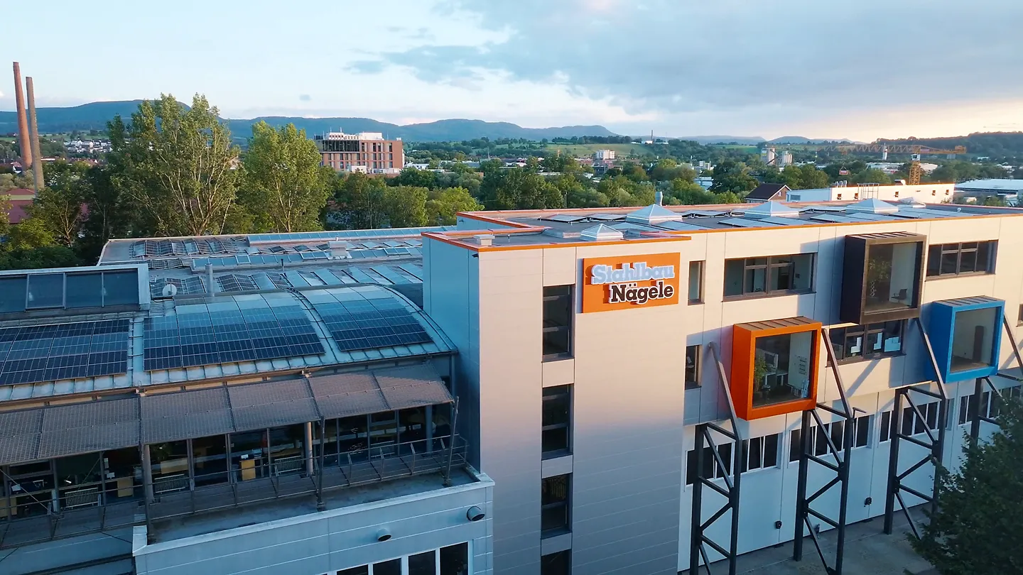 Firmengebäude Stahlbau Nägele mit modernen Büros, Solarzellen auf dem Dach und Blick auf Umgebung.