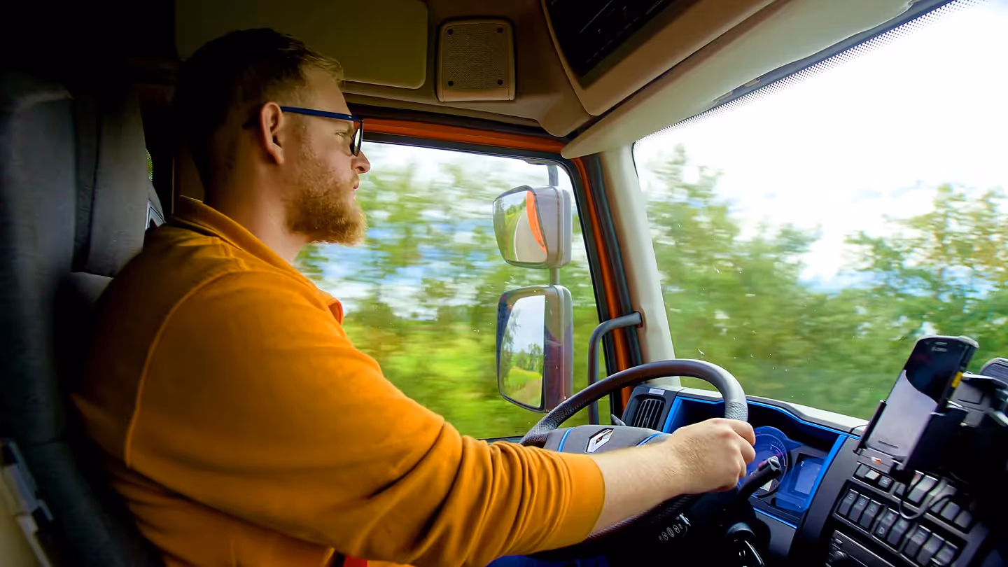 Lkw-Fahrer steuert Lastwagen auf Autobahn, Innenaufnahme aus Fahrerhaus während der Fahrt.