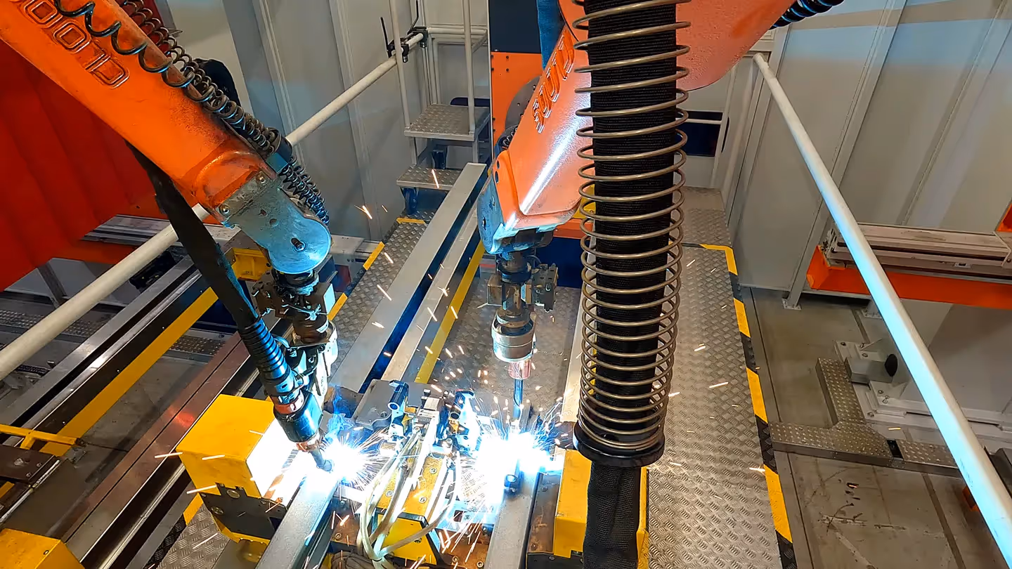 Industrieroboter schweißen Metallbauteile mit hoher Präzision in einer modernen Fertigungslinie bei KION, Funkenflug und Automatisierungstechnik sichtbar.