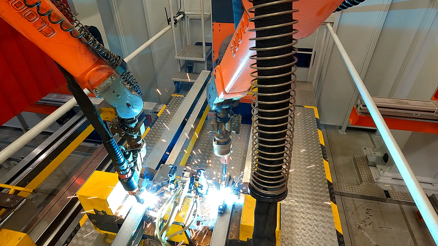 Industrieroboter schweißen Metallbauteile mit hoher Präzision in einer modernen Fertigungslinie bei KION, Funkenflug und Automatisierungstechnik sichtbar.