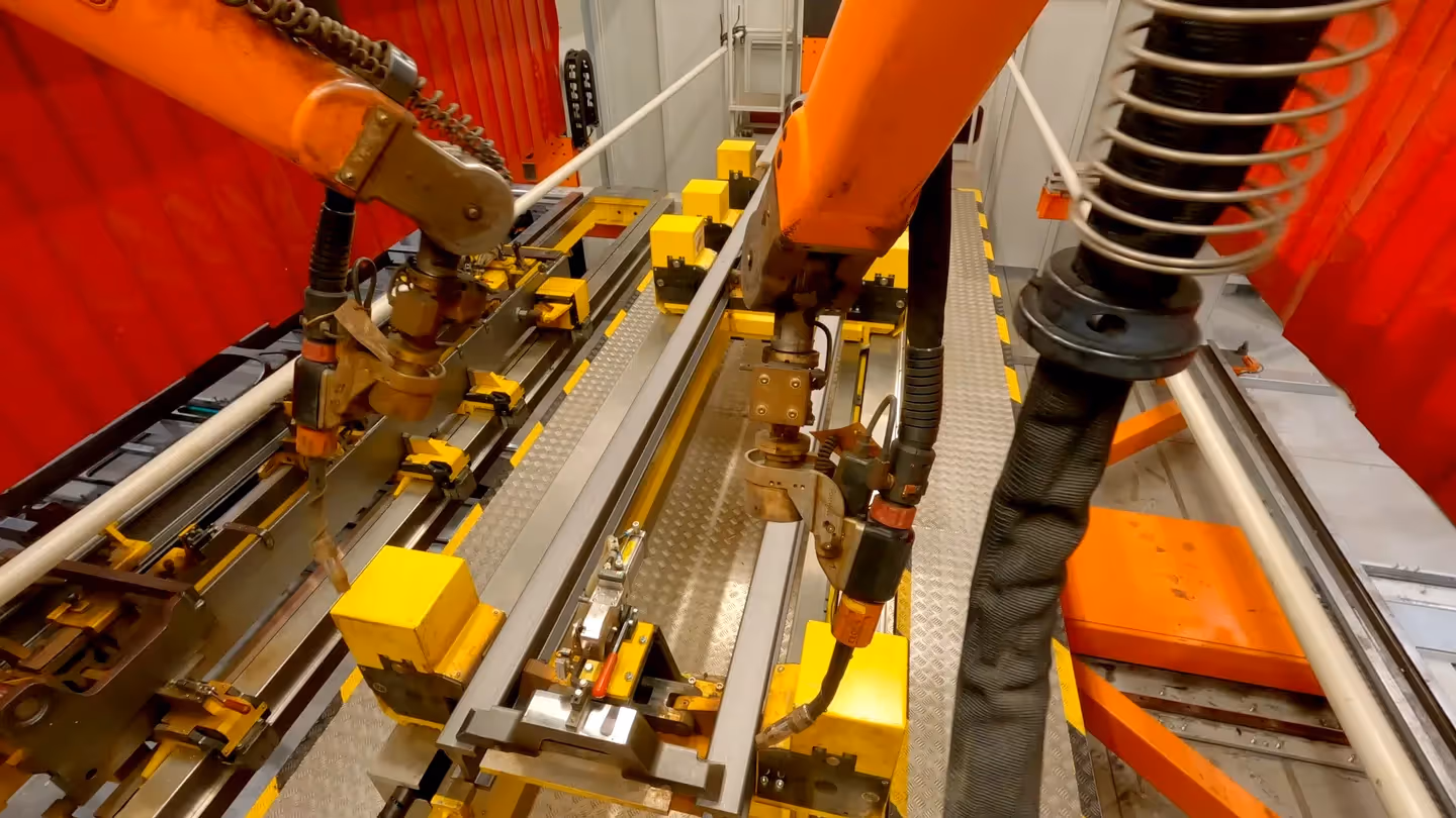 Industrieroboter beim Schweißen von Metallrahmen in der KION Produktion, automatisierte Fertigung mit gelben Vorrichtungen und präziser Robotertechnik.