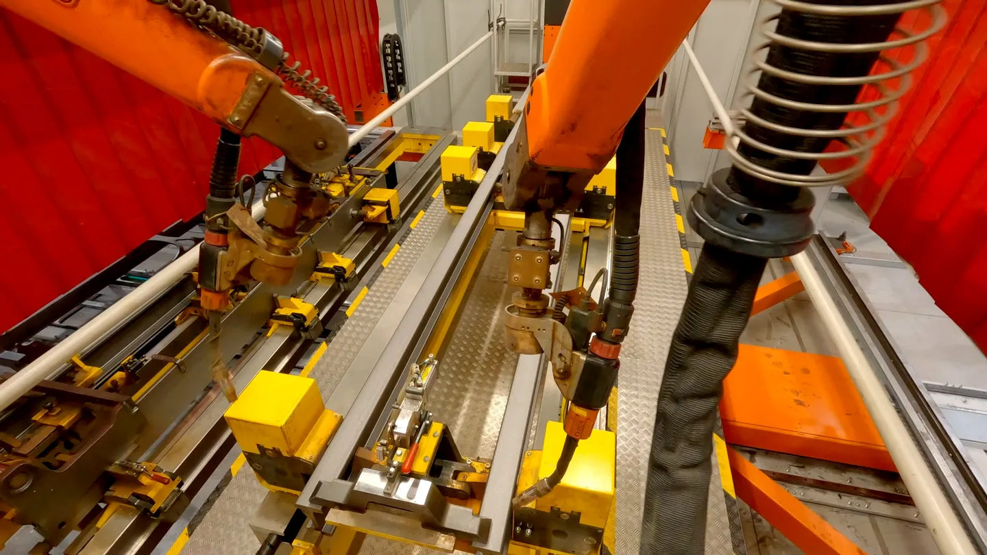 Industrieroboter beim Schweißen von Metallrahmen in der KION Produktion, automatisierte Fertigung mit gelben Vorrichtungen und präziser Robotertechnik.