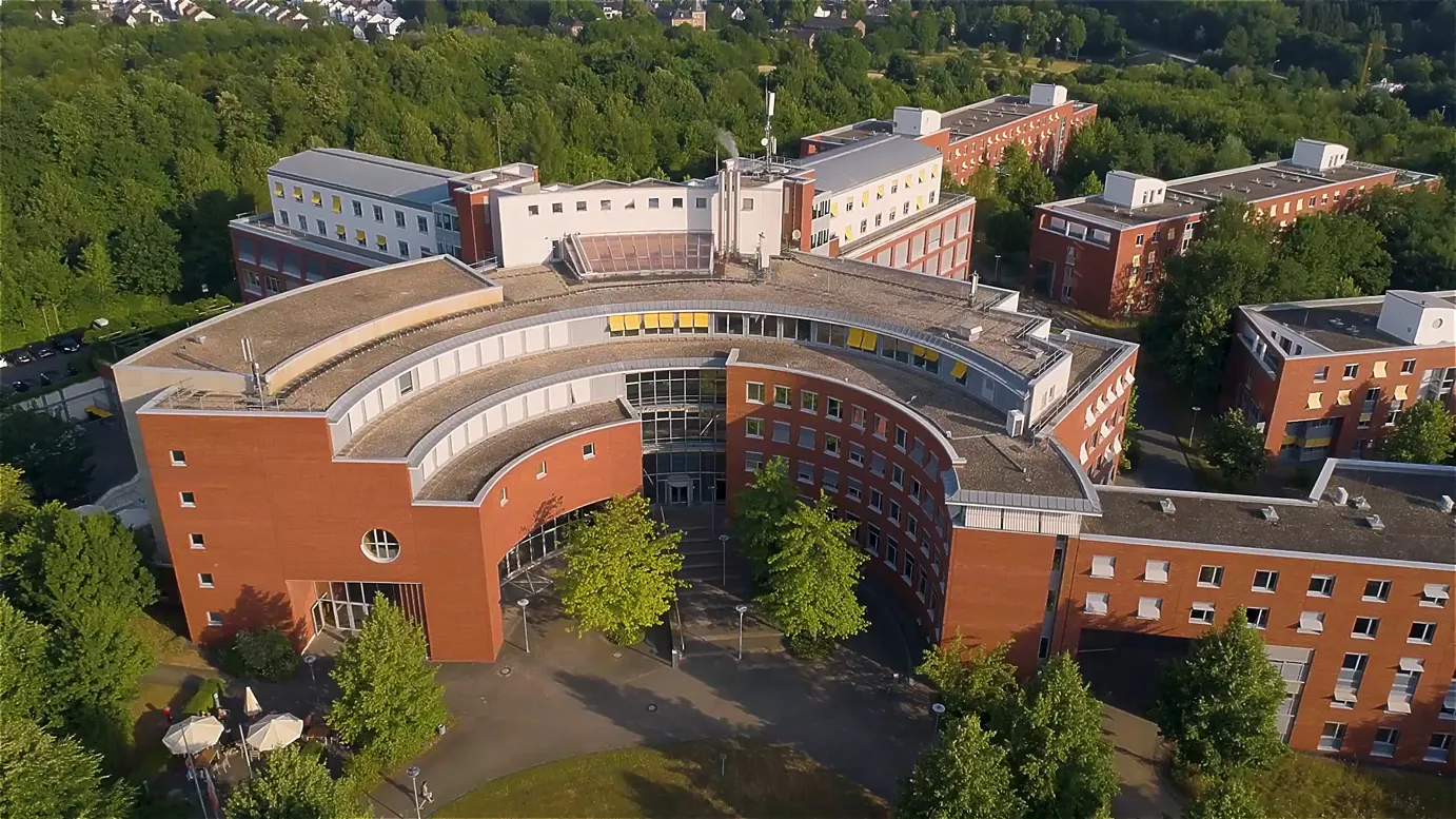 Recruitingfilm Szene: Luftaufnahme der Hochschule des Bundes mit rotem Backsteingebäude – filmische Darstellung des Studiengangs Cyber-Sicherheit, moderner Campusarchitektur und Bildung in professioneller Filmproduktion.