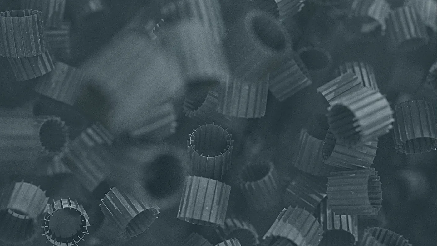 3D rendering of cylindrical plastic filter media elements, used in wastewater treatment processes, shown in close-up detail.