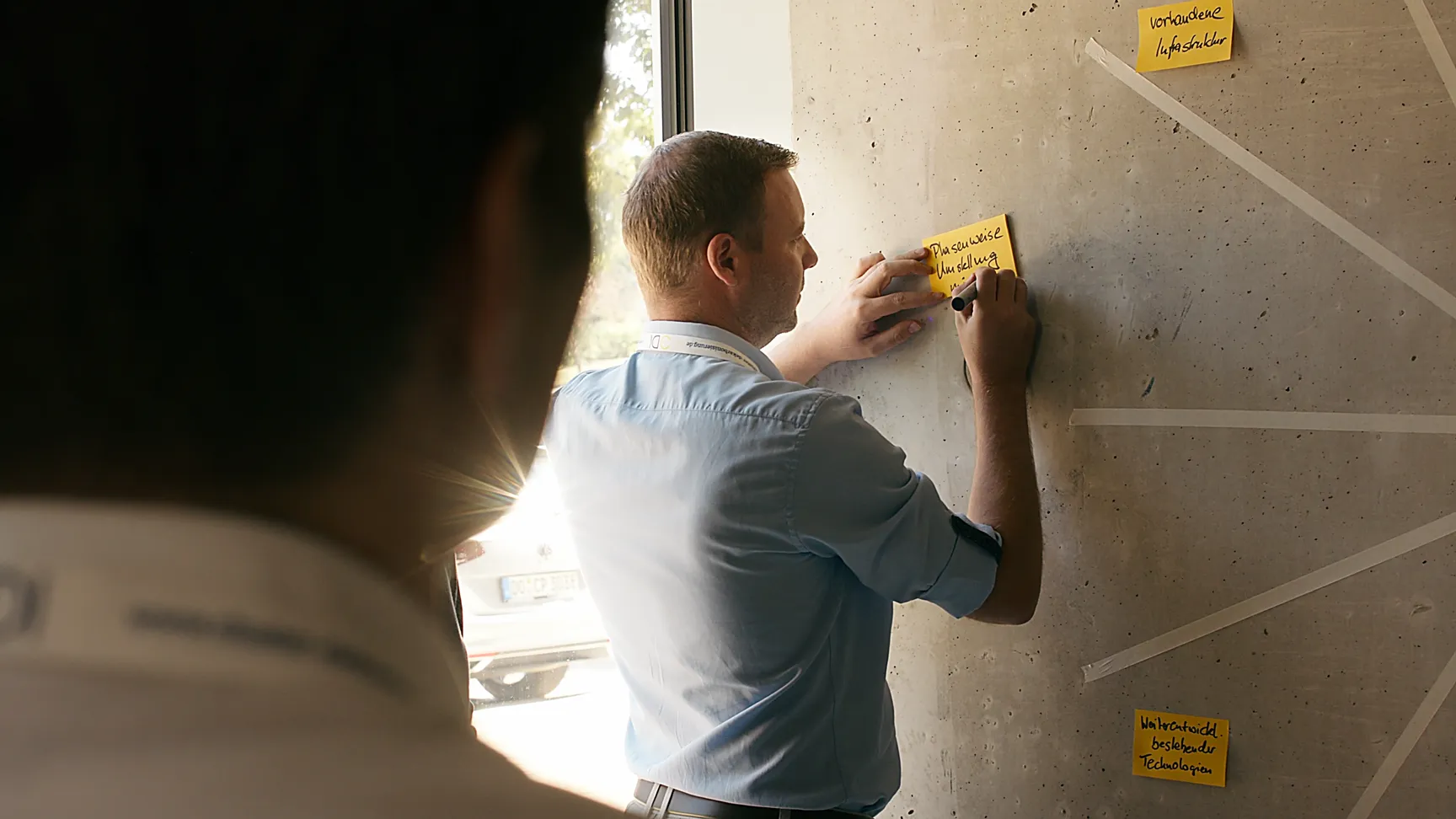 Workshop-Szene beim CDI Summit, Teilnehmer schreibt Ideen zur Dekarbonisierung auf Post-it an Wand.