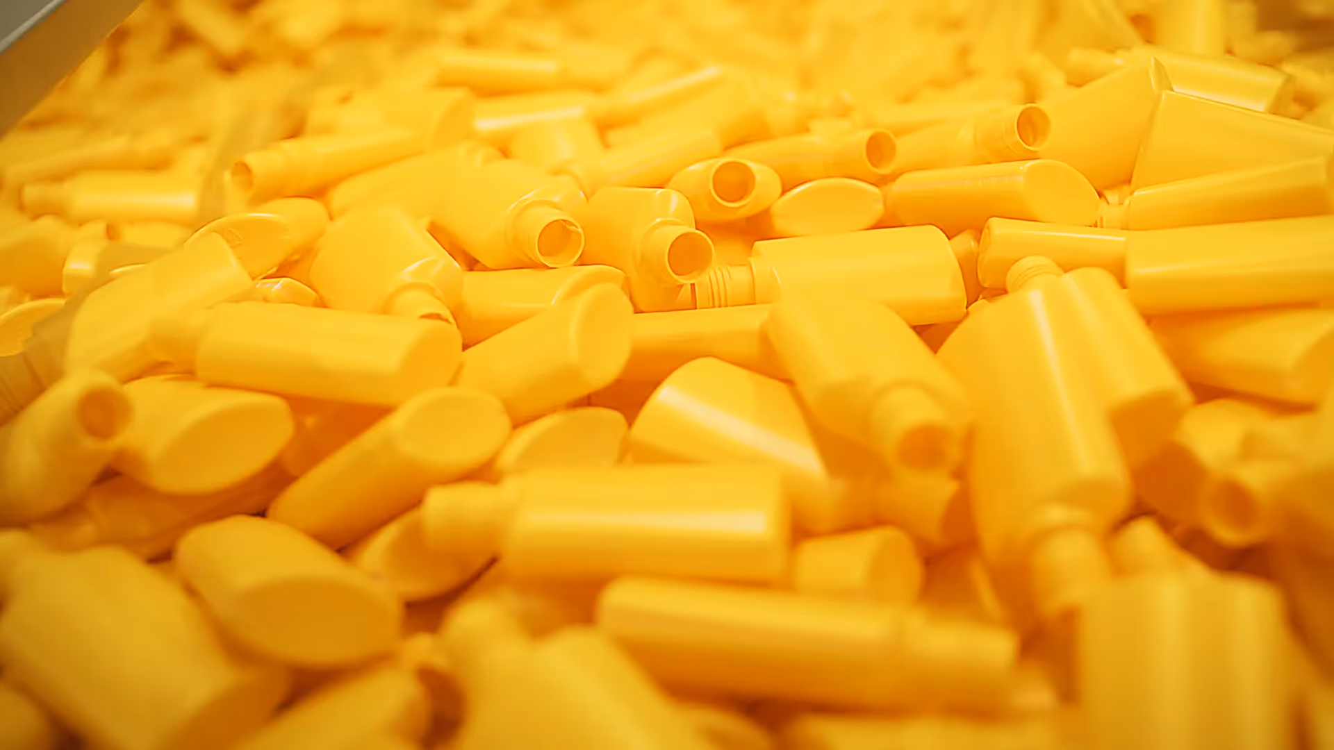 Detailaufnahme gelber Kunststoffflaschen in der Fertigung – eingefangen in einer modernen Filmproduktion oder einem Werbefilm, der industrielle Präzision, Effizienz und Qualität in der Produktproduktion visuell hervorhebt.