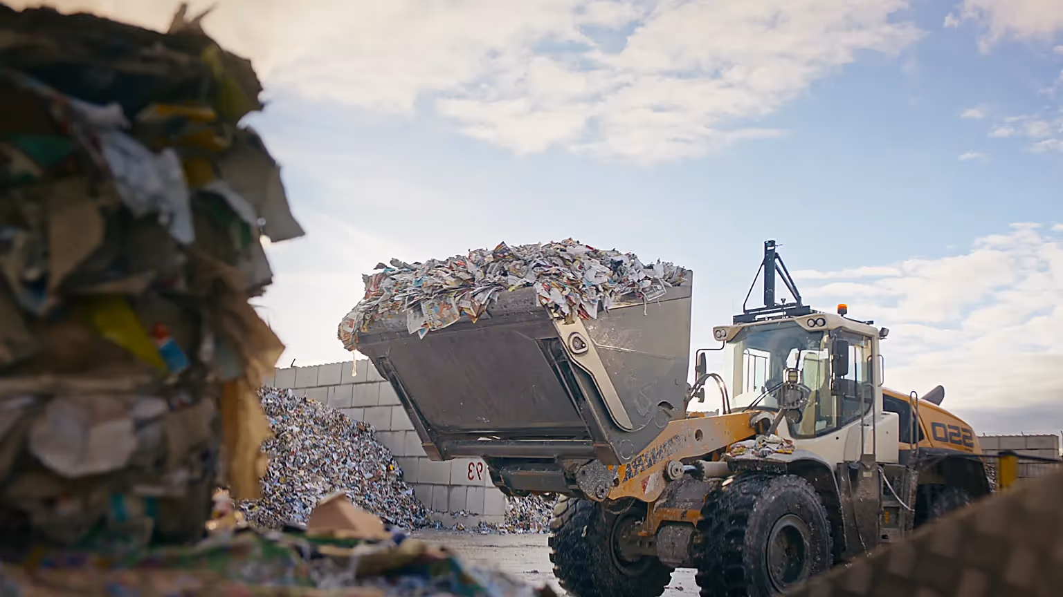 Baumaschine lädt Recyclingmaterial für nachhaltige Kreislaufwirtschaft.