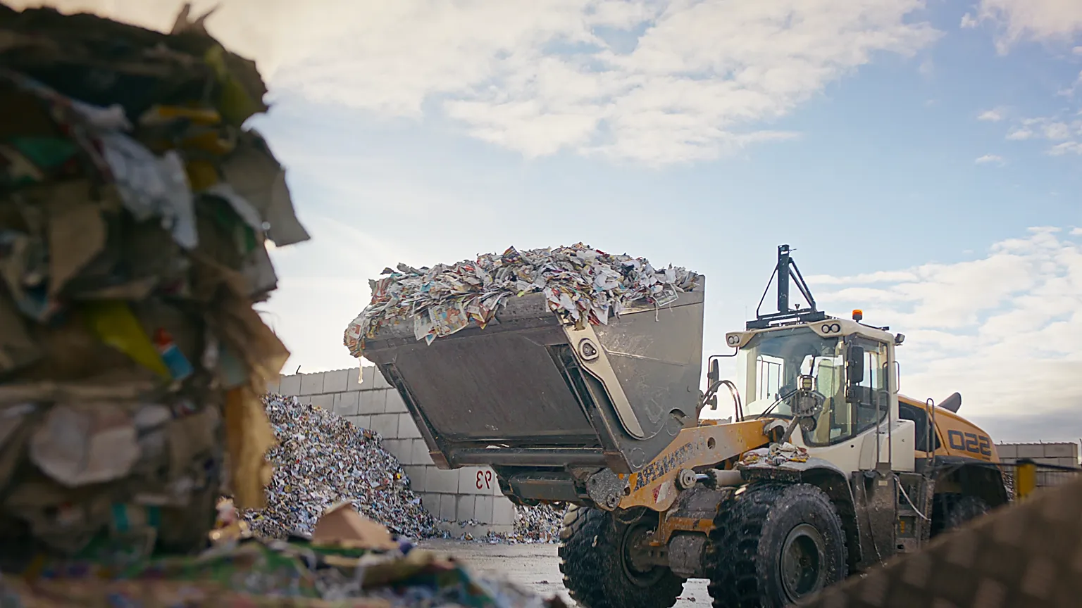 Baumaschine lädt Recyclingmaterial für nachhaltige Kreislaufwirtschaft.