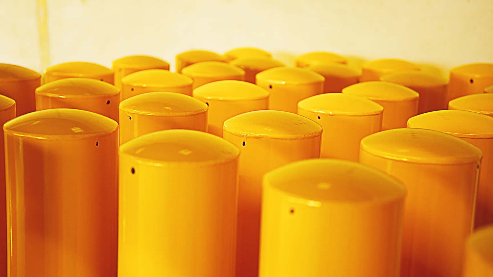 Filmproduktion und Imagefilm-Visualisierung: Nahaufnahme gelb lackierter Metallzylinder – industrielle Produktionsästhetik für Recruitingfilm oder Unternehmensfilm mit Fokus auf Präzision, Qualität und Fertigungstechnik.