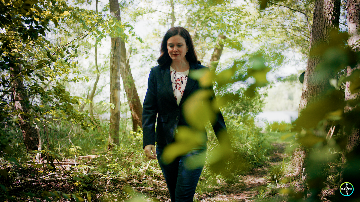 Frau spaziert durch einen grünen Wald – natürliche Szene aus einem Imagefilm, der Unternehmenswerte und Nachhaltigkeit in filmischer Bildsprache vermittelt.