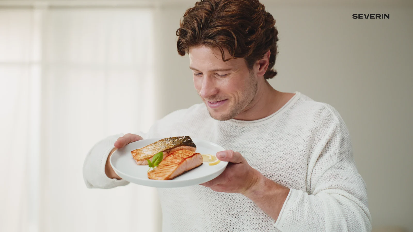 Werbefilm für SEVERIN: Mann hält einen Teller mit Lachs aus der S-Fry Digital AI Heißluftfritteuse. Studiodreh einer professionellen Filmproduktion für Produktlaunch und Social-Media-Kampagne.