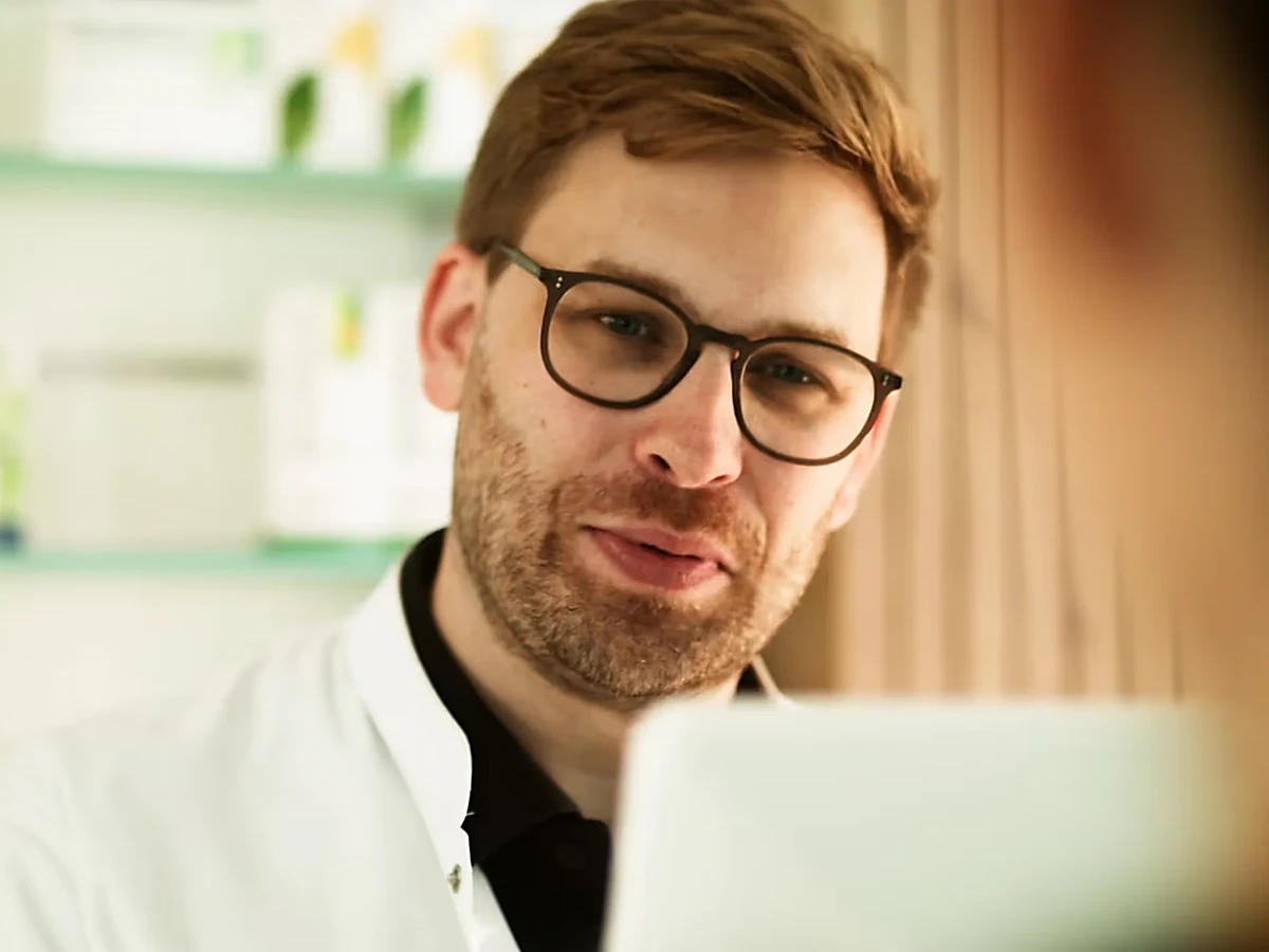 Apotheker mit Brille im Gespräch, Szene aus dem Produktvideo für Arvato Mediverse
