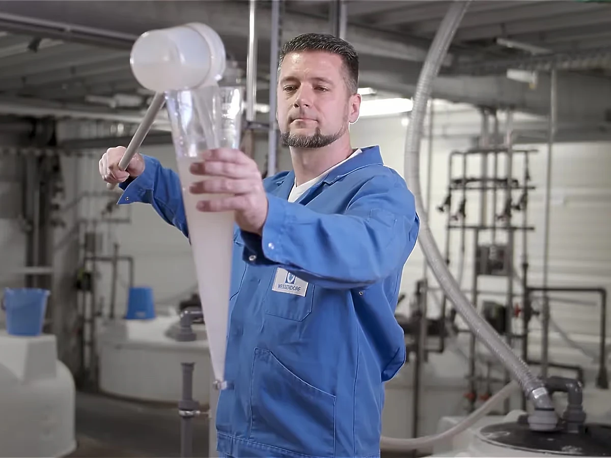 Mitarbeiter im blauen Kittel prüft eine Probe in der Tetra-Produktion, Szene aus dem Imagefilm für Tetra