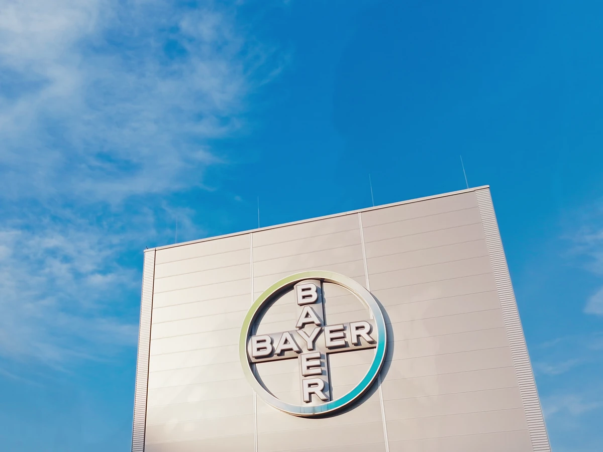Bayer-Kreuz an einem Werksgebäude vor blauem Himmel, Szene aus dem Imagefilm für Bayer Nubeqa
