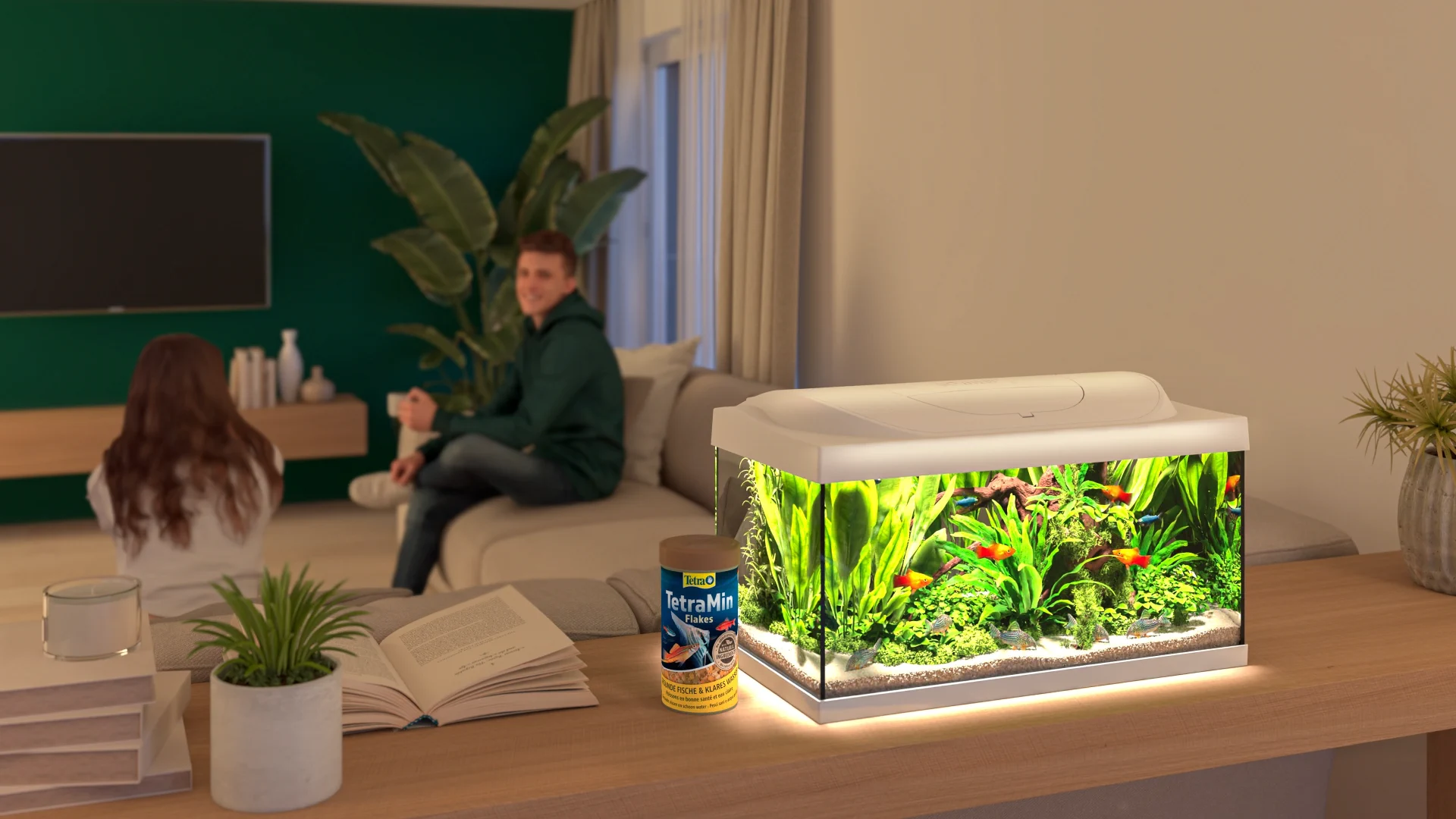 Gerenderte Wohnzimmerszene: Aquarium mit bunten Fischen und eine Dose TetraMin auf einem Holzsideboard, im Hintergrund zwei Personen
