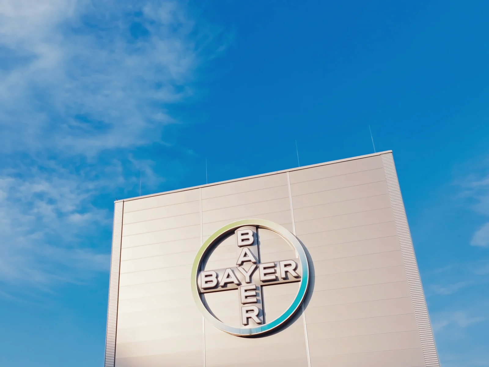 Bayer-Kreuz an einem Werksgebäude vor blauem Himmel, Szene aus dem Imagefilm für Bayer Nubeqa