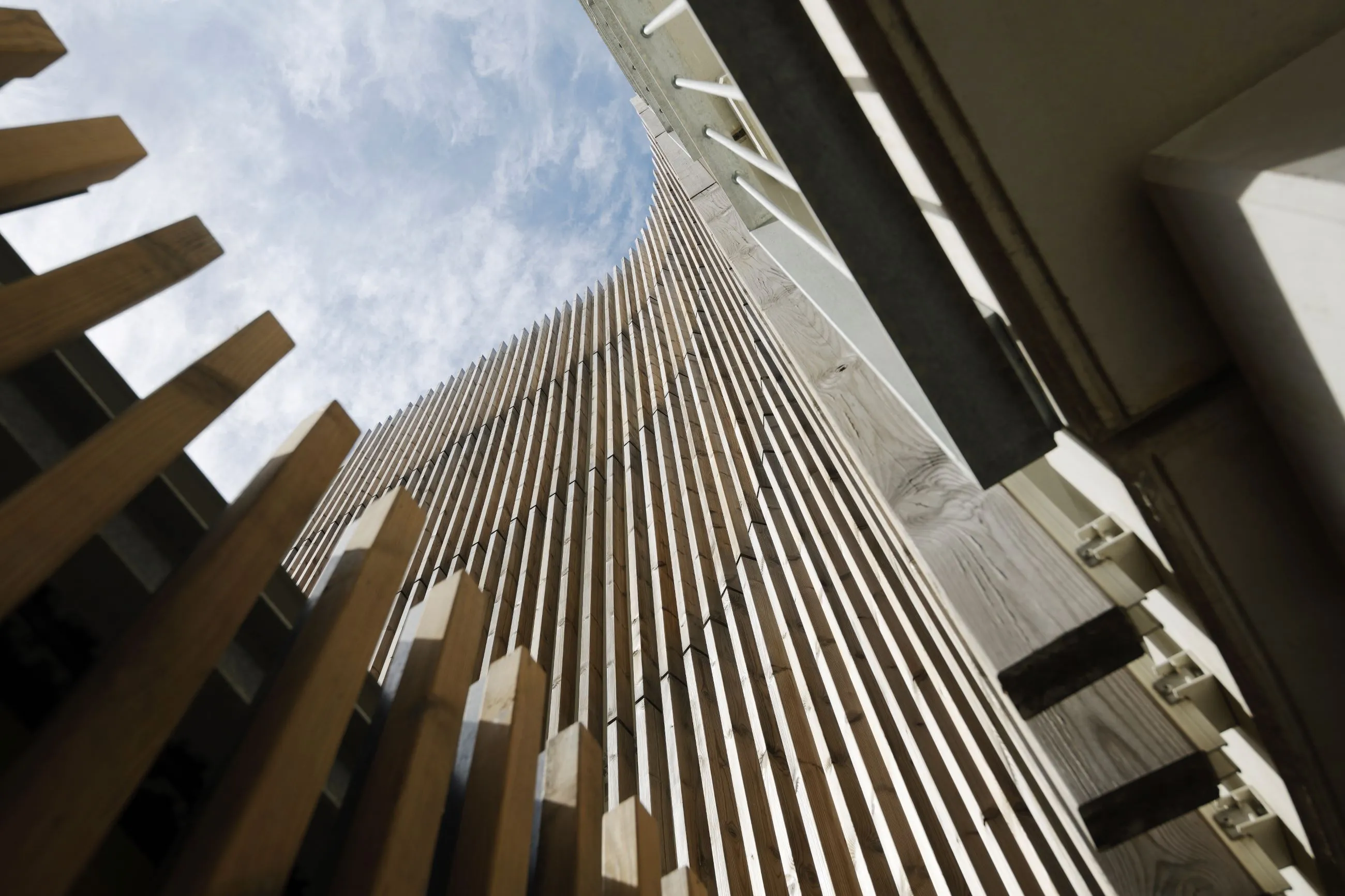 Woodfac Click, Holzlamellen: gebogene Holzlamellenfassade, Blick von unten in den Himmel
