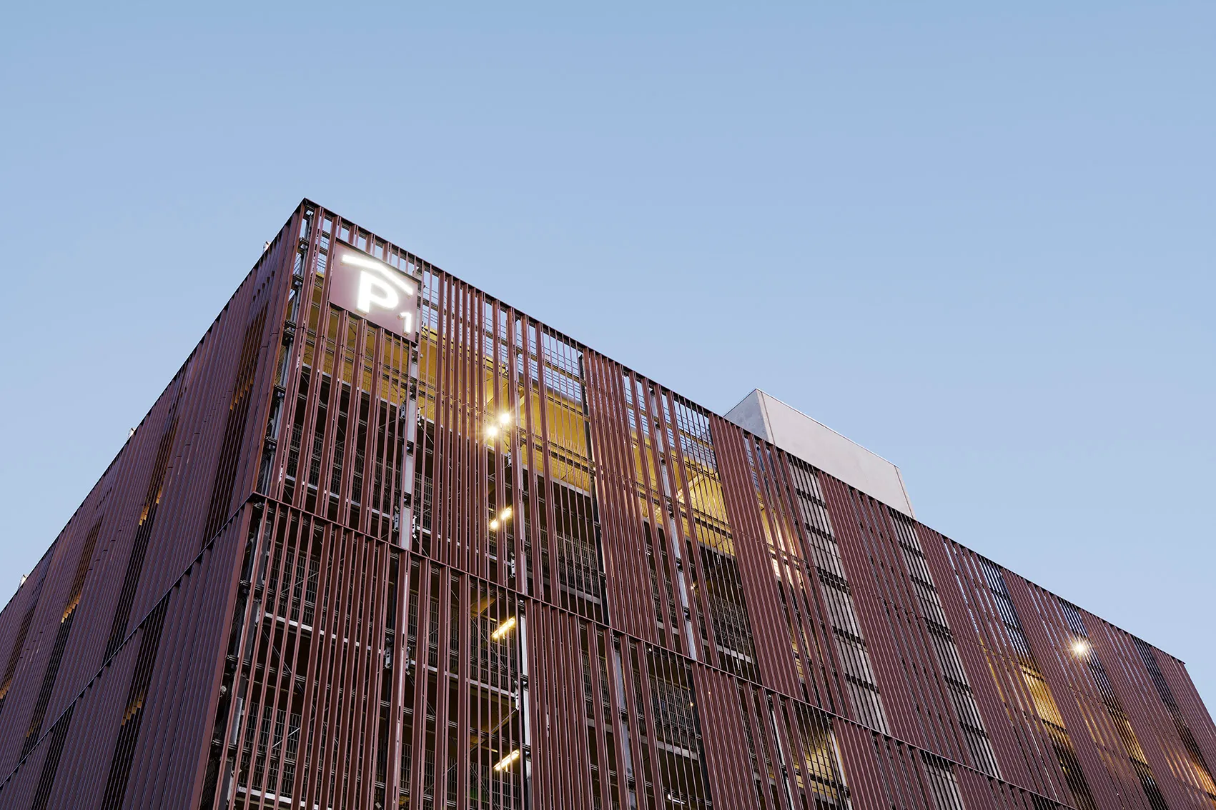 Parkhaus Design City Kolding mit Napsu-Aluminiumlamellen, Gebäudeecke mit P1-Schild in der Dämmerung