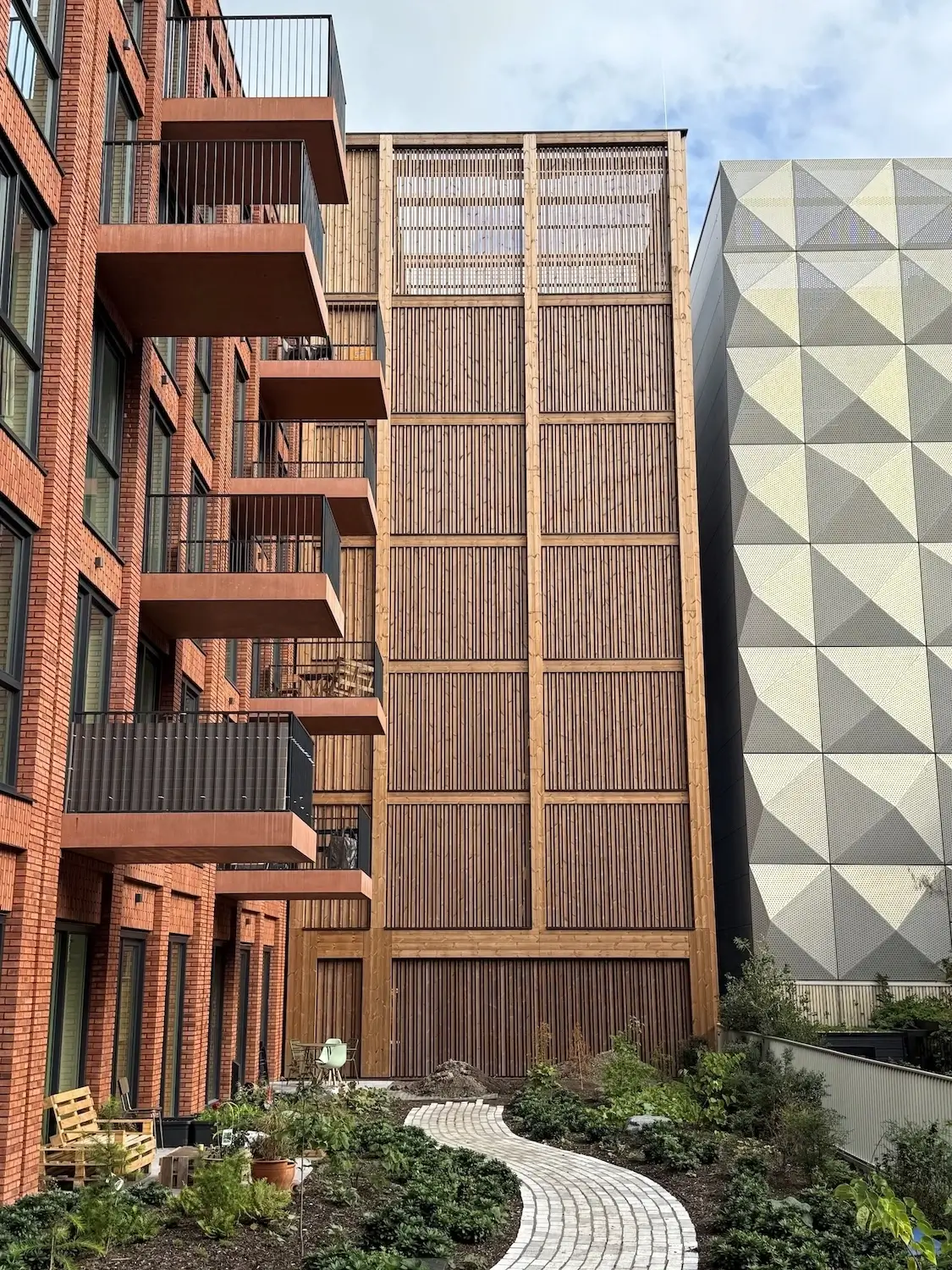 Parkhaus Distelweg in Amsterdam: Holzlamellenfassade im Hof zwischen Backsteinwohnbau und Nachbarfassade
