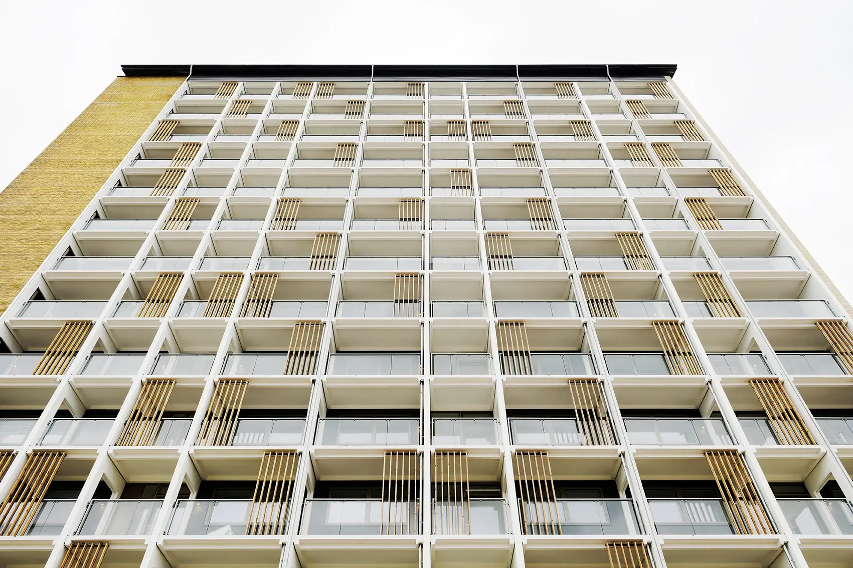 Hochhaus Birkeparken in Odense von unten, Balkone mit Holzlamellen aus Woodfac Click vor heller Fassade