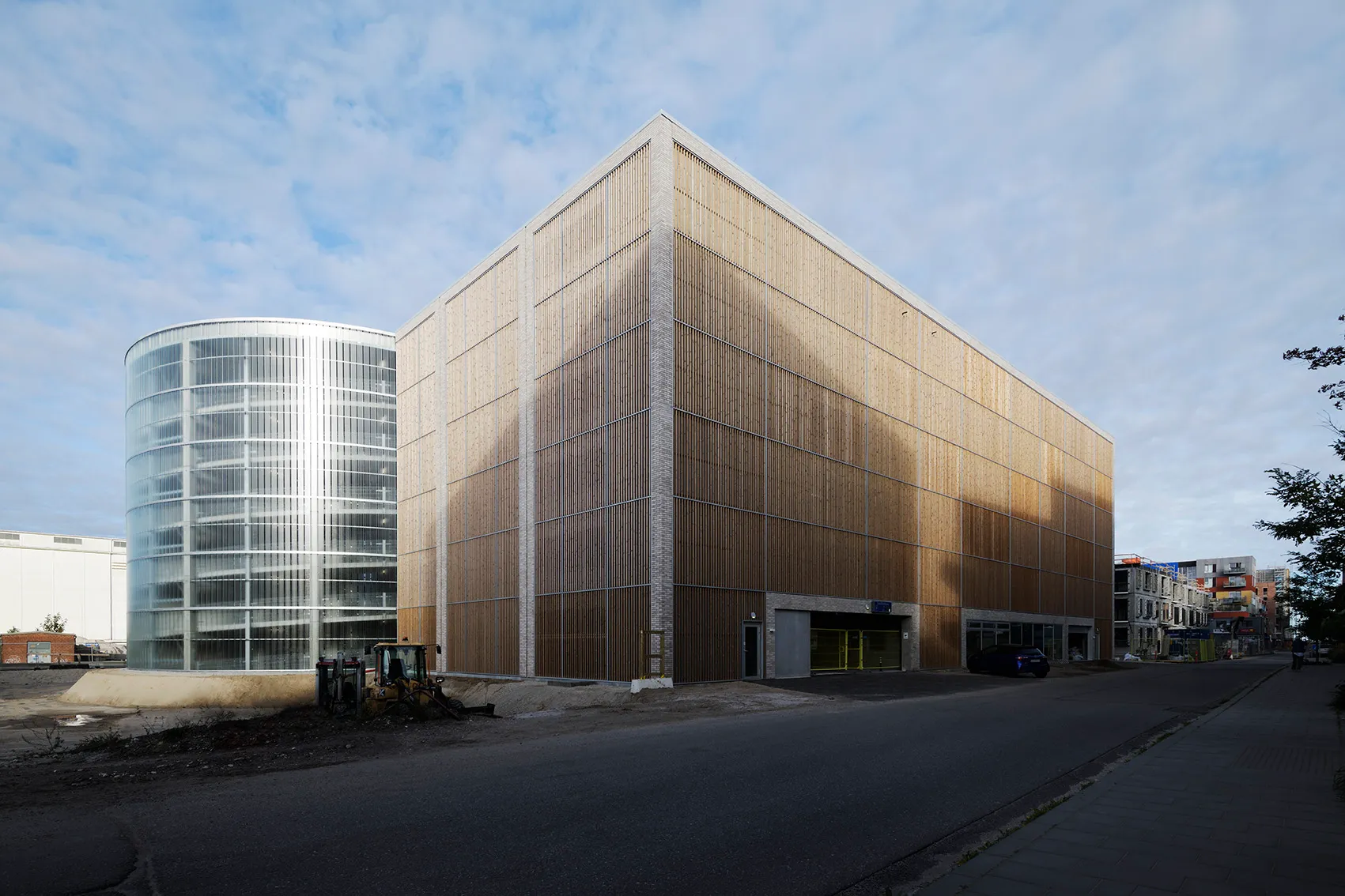 Parkhaus Søndre Havn mit Holzlamellenfassade neben einem runden Glasturm, Straßenansicht