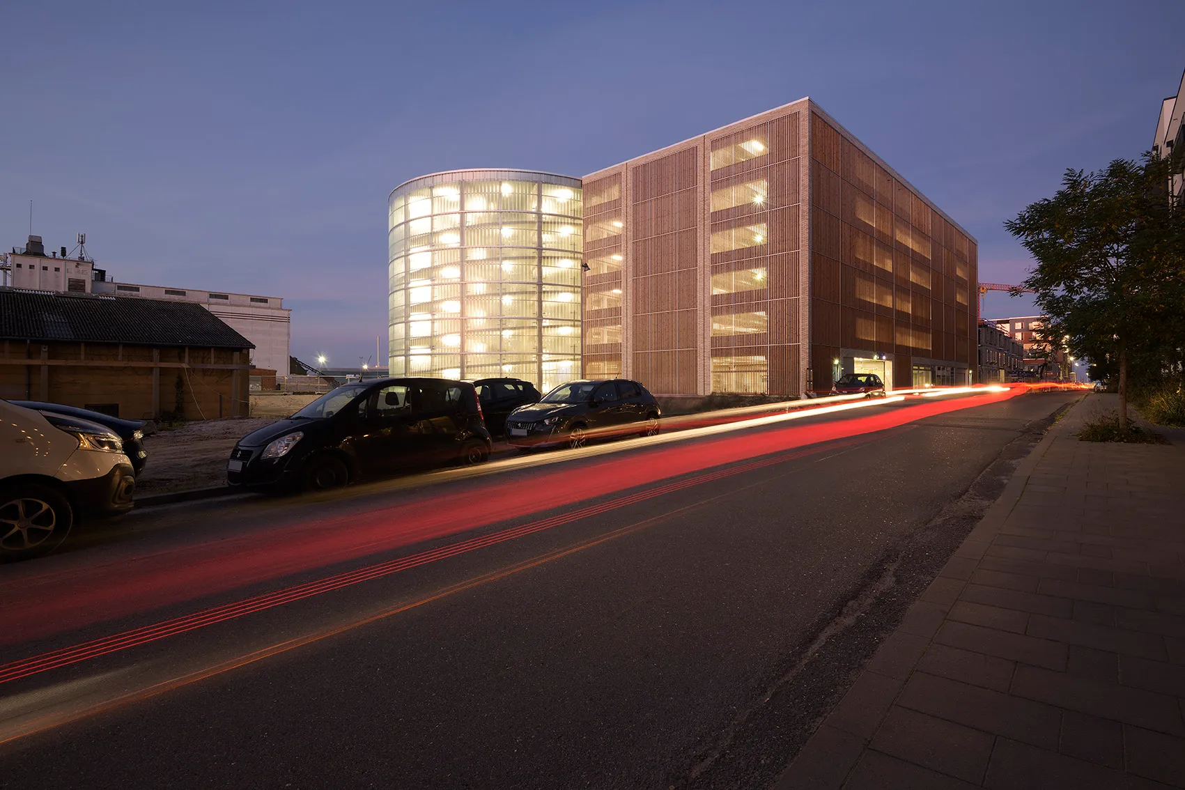 Parkhaus Søndre Havn mit beleuchteter Fassade in der Dämmerung, Straße mit Lichtspuren, Woodfac Click & Napsu