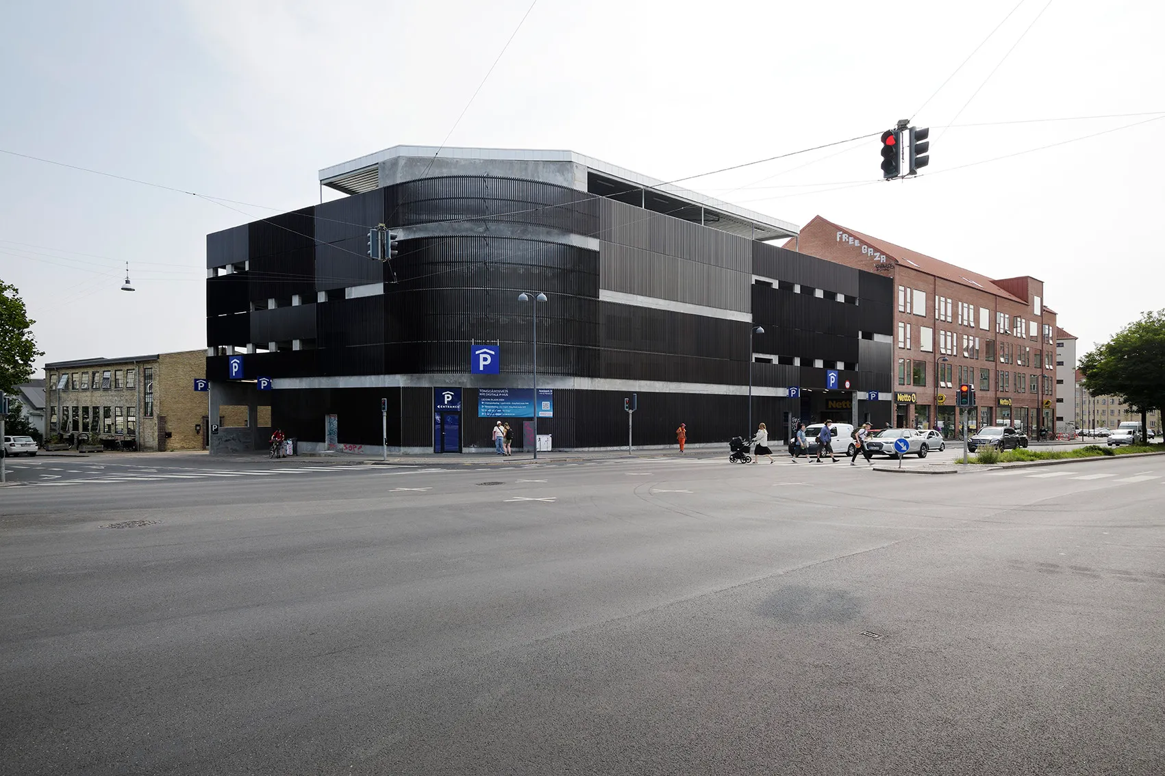 Parkhaus Tomsgårdsvej mit dunkler Napsu Lamellenfassade an einer Straßenkreuzung, KANT Arkitekter