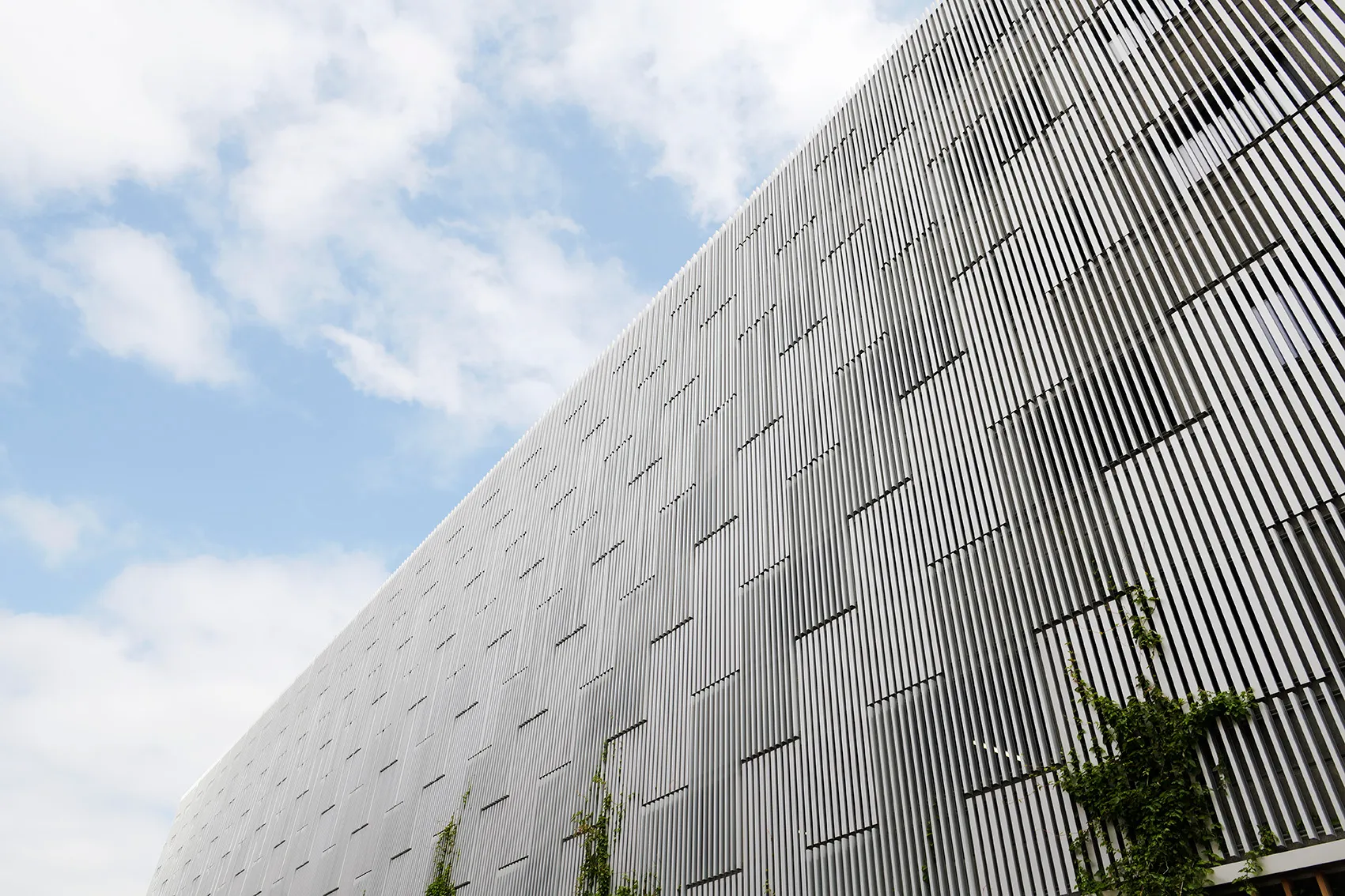 Lamellenfassade von Stigsborg in Schrägansicht mit Pflanzen, Napsu