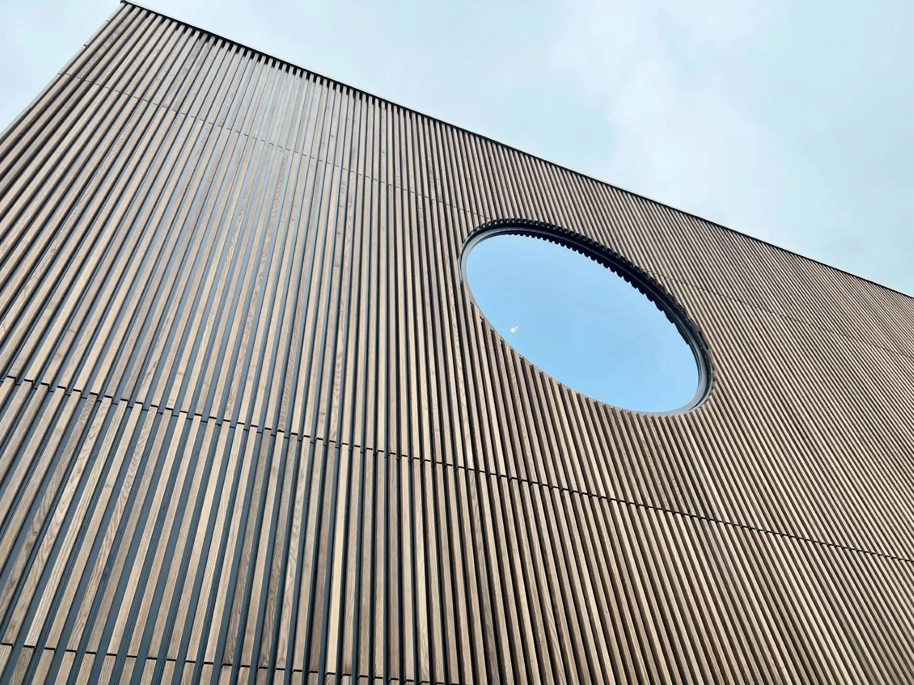 Fassade des Comwell Hotel Middelfart mit dunklen Woodfac Panel Holzlamellen und rundem Fenster