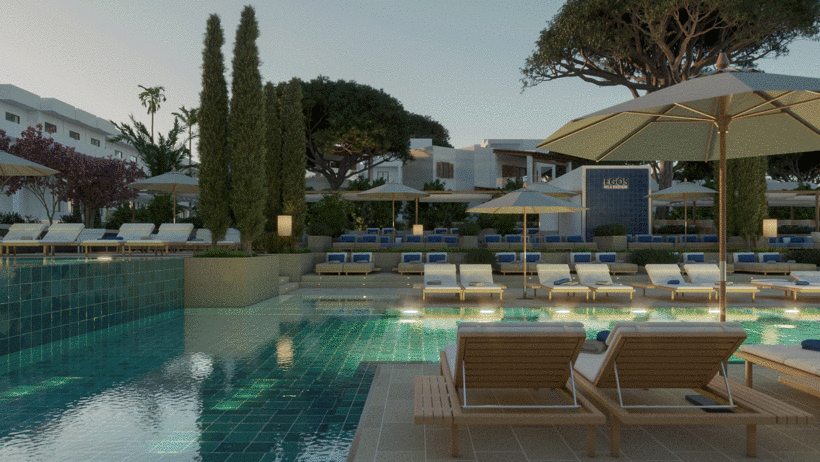 Área de piscina ao ar livre em resort ao entardecer, com espreguiçadeiras de madeira e guarda-sóis brancos.