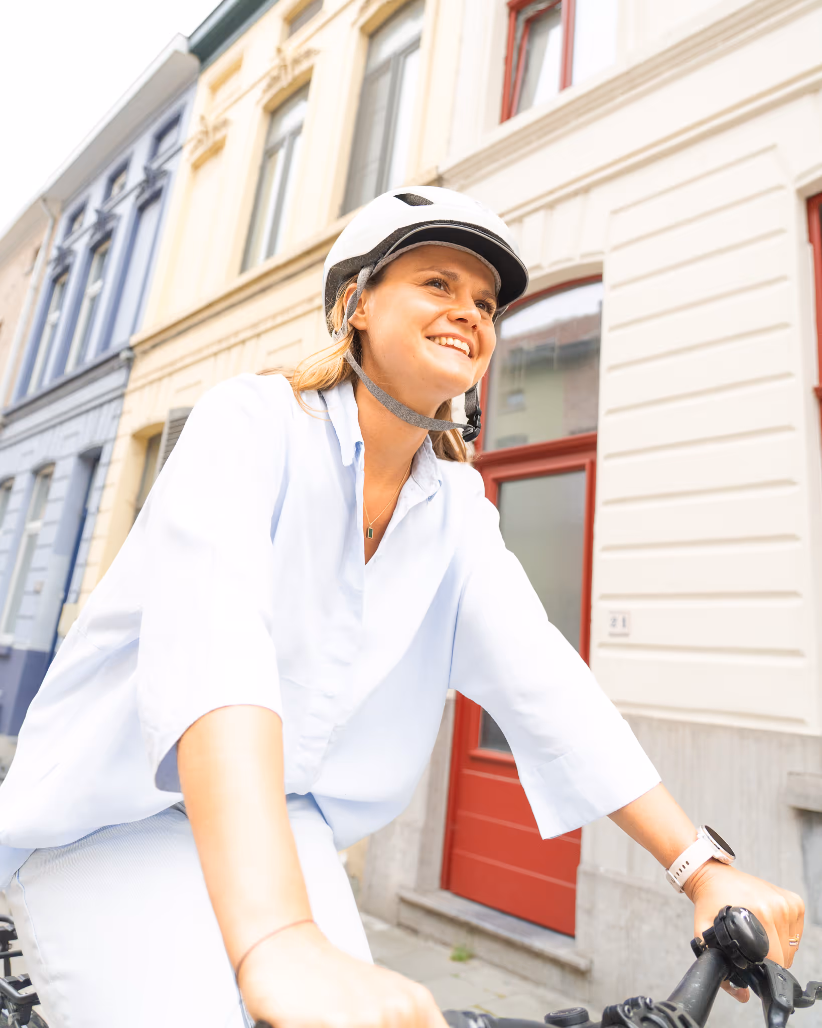 vrouw met lach op leasefiets en witte helm dankzij fietsleasing